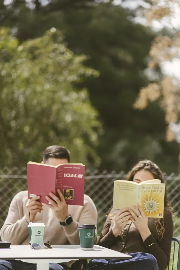 Two friends reading books over coffee at an outdoor table