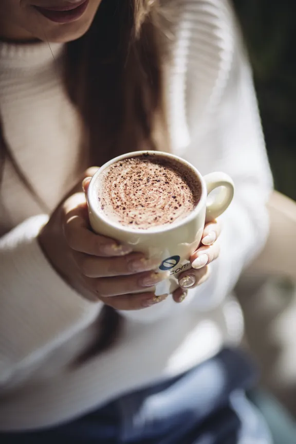 Hands cradling a warm Kawacom's cappuccino
