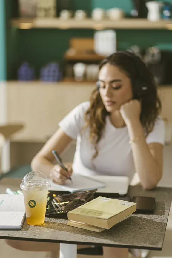 Studying at a café table with an iced Kawacom's coffee